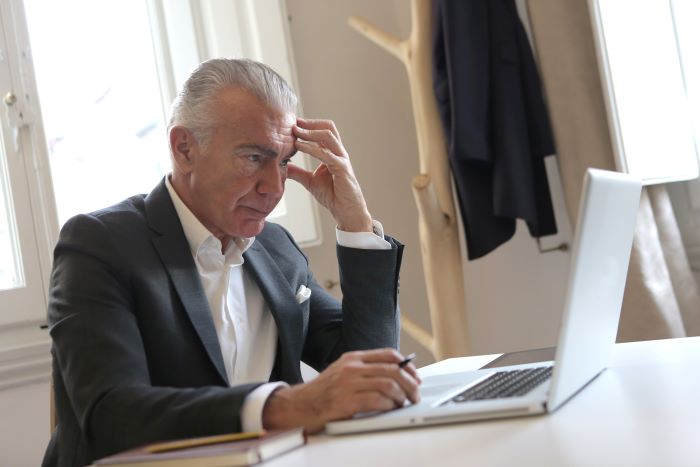 man-in-black-suit-jacket-while-using-laptop-700