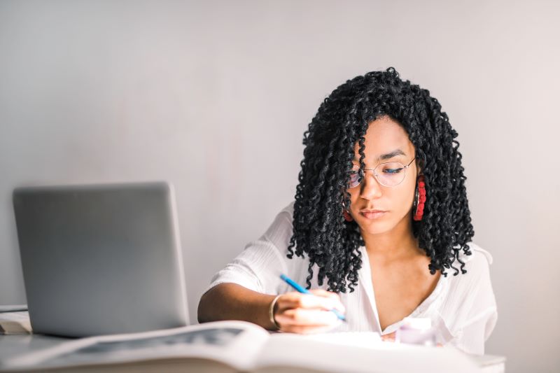 woman-in-white-polo-shirt-holding-a-pen-near-laptop