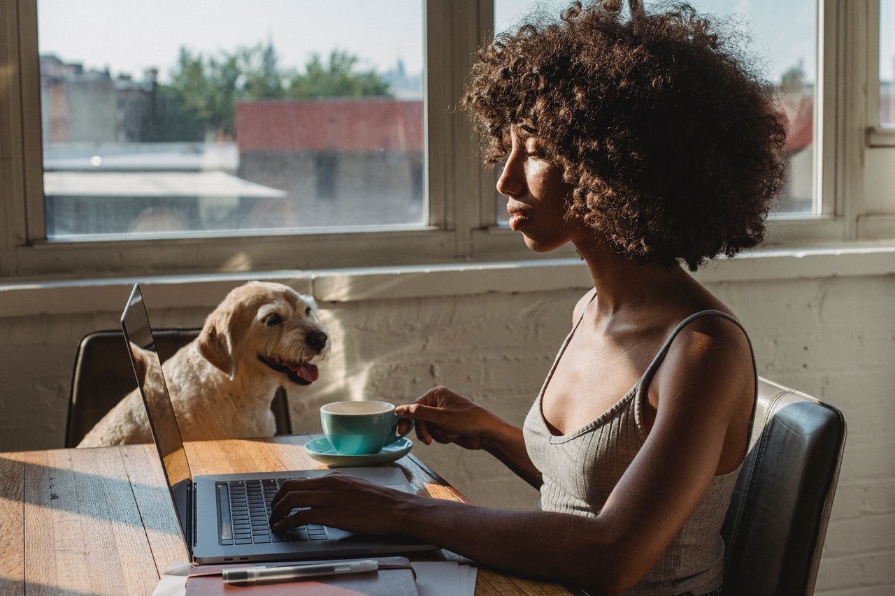 female-with-coffee-typing-near-dog