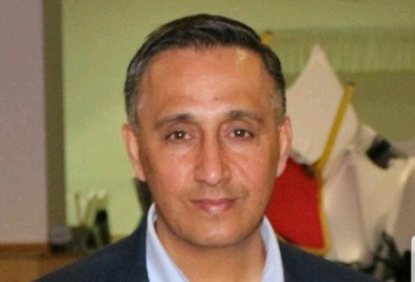 An Asian man in blue shirt and dark jacket