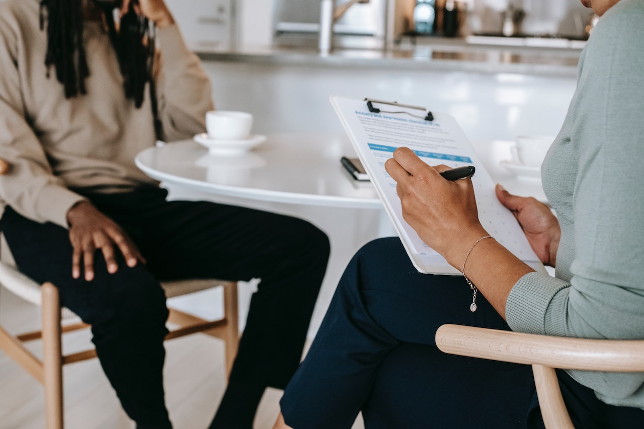 two people sat opposite each other in a meeting, one holding a clipboard