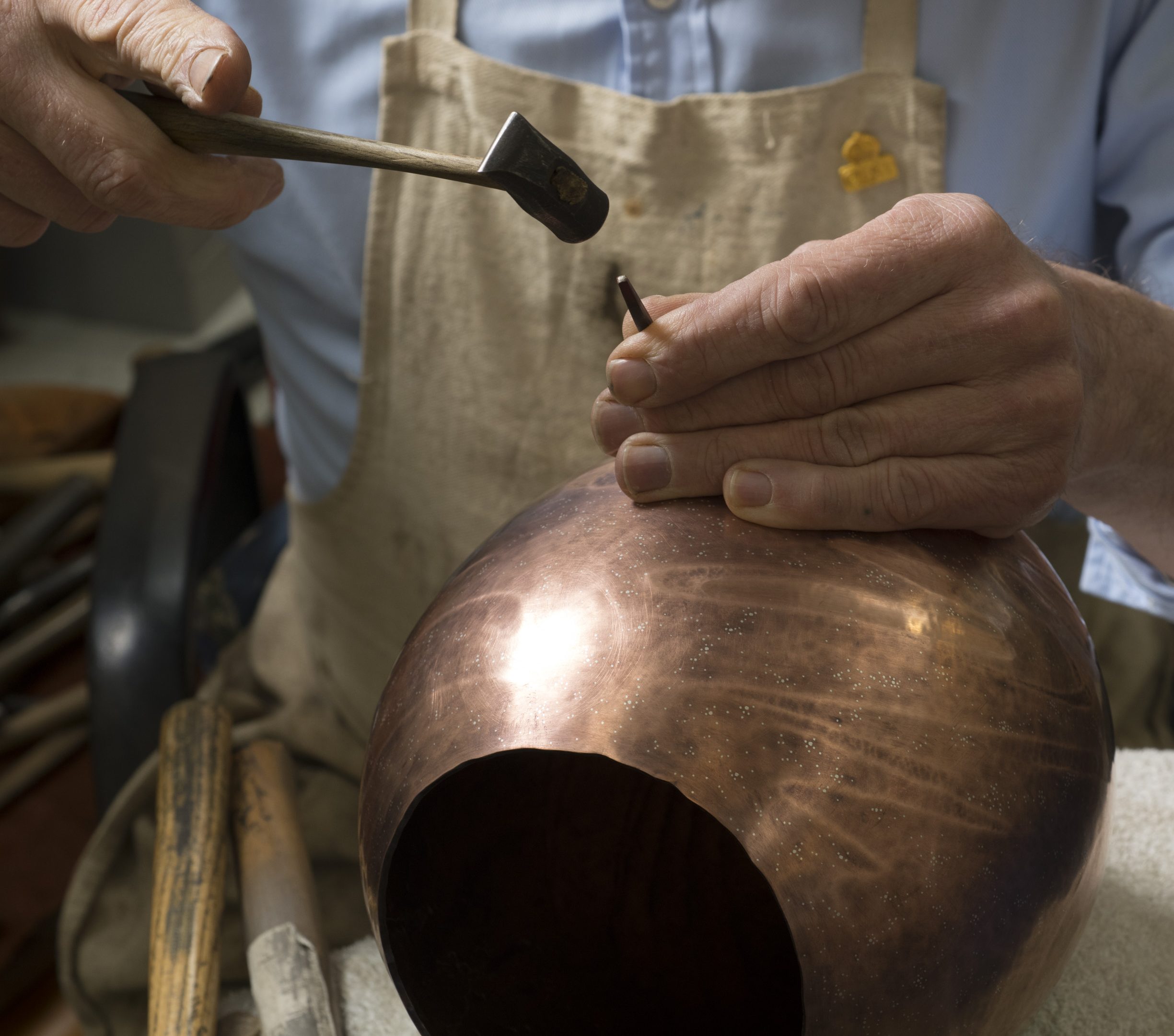 craft person working on copper pot
