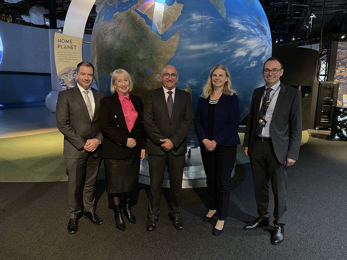 Five people standing in front of large globe