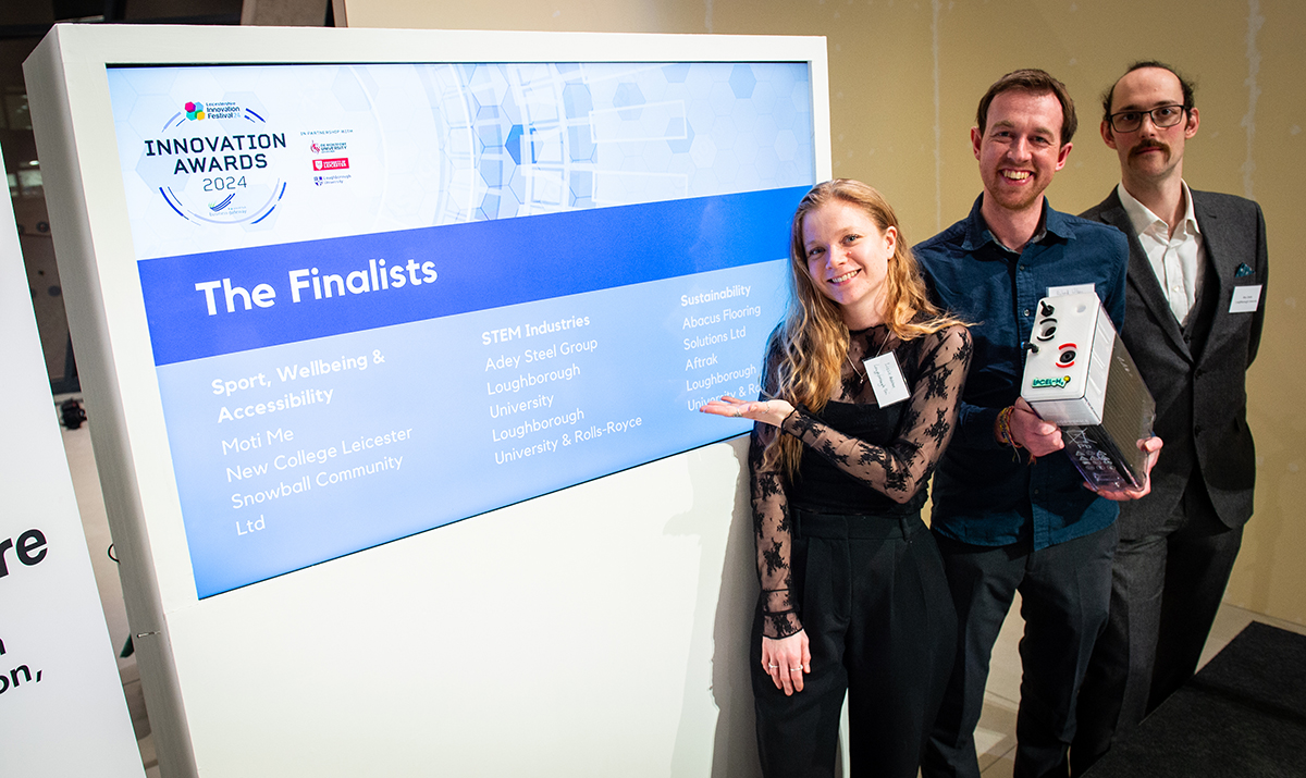 Three people standing by powerpoint screen